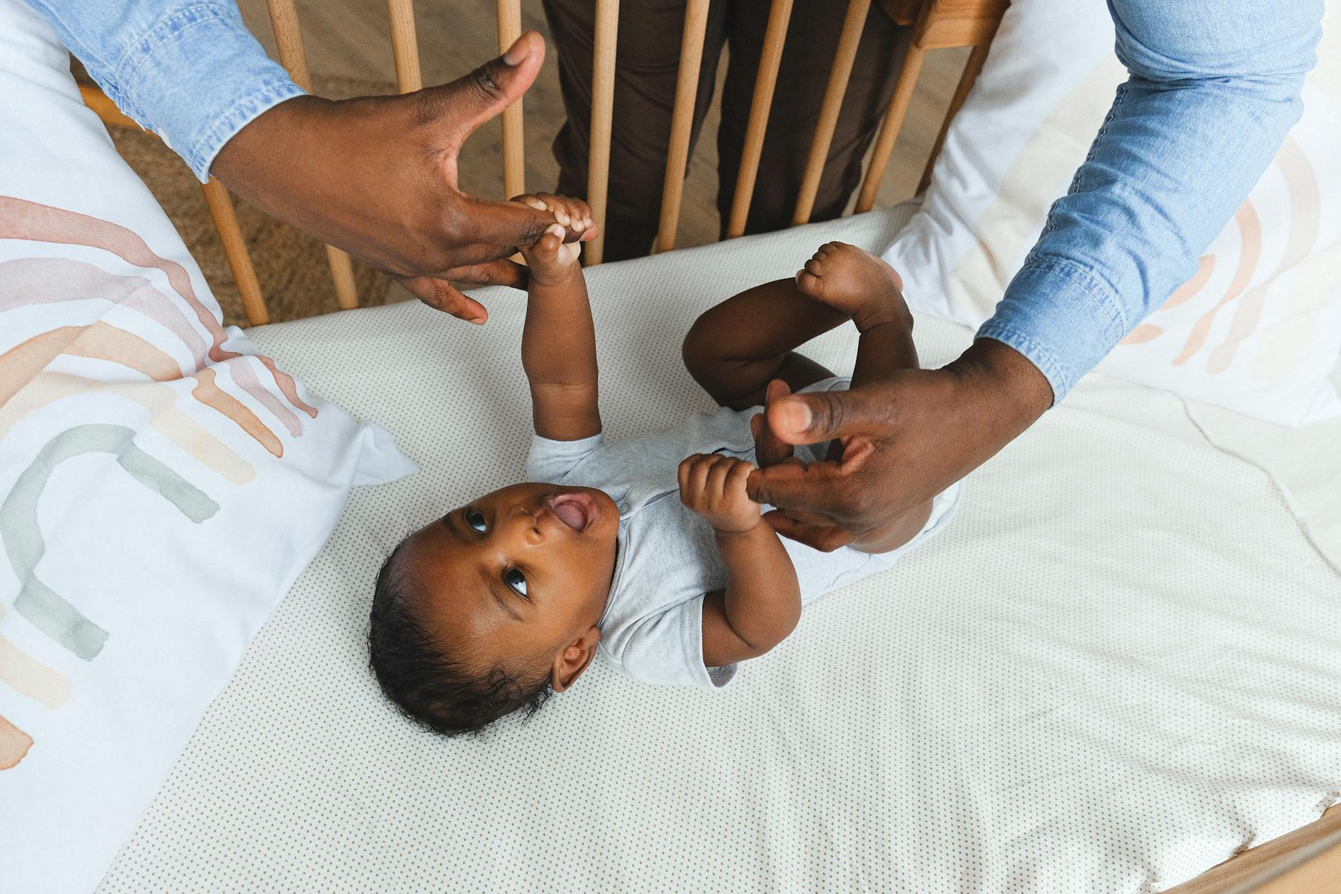 Parent gently with their baby in the crib