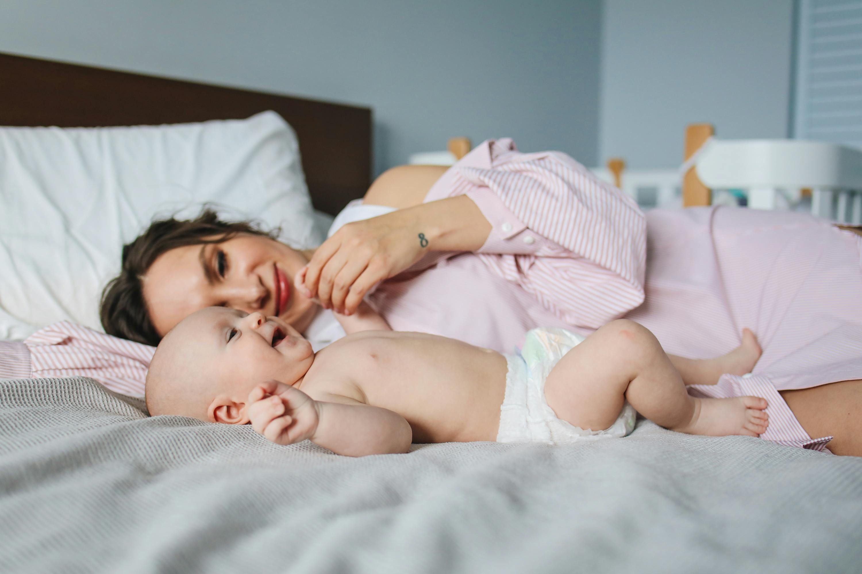 Mother lying on bed beside her baby
