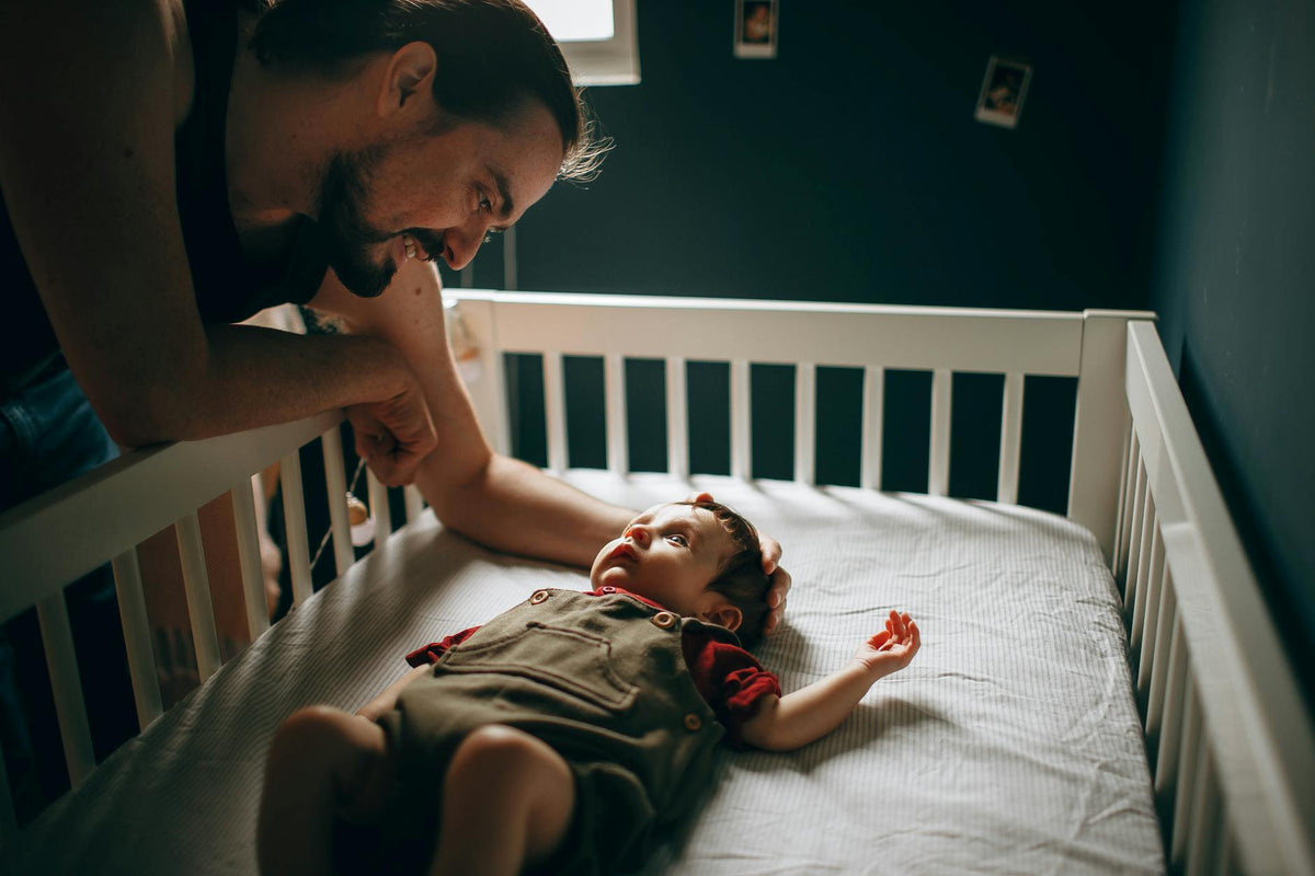 Father gently looking at his baby in the crib